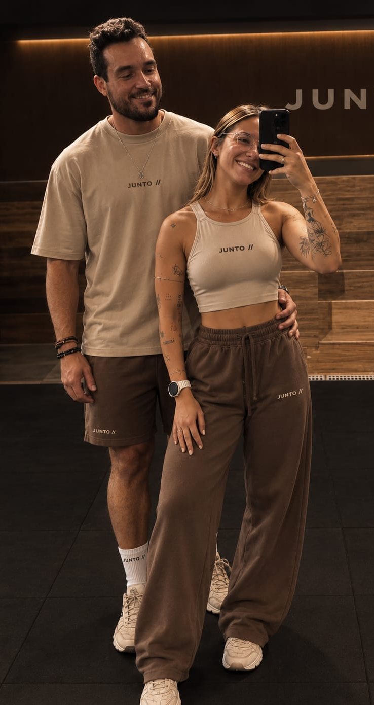 Casal fazendo selfie no espelho com camiseta areia, regata e calça moletom marrom